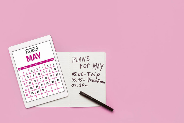 Сучасний планшетний комп'ютер з календарем і блокнотом з планами на травень на рожевому фоні
 - Фото, зображення