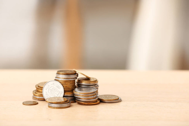 Stacks of coins on wooden table against blurred background - Foto, Imagen