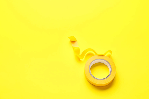 Rouleau de ruban adhésif sur fond jaune
 - Photo, image
