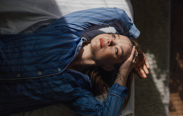 Top view of woman lying in a bed,morning sun shining on her face. - Foto, afbeelding