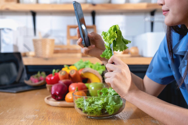 Dieta, mladá Asiatka s bílou kůží v modré košili, která jí zeleninový salát a jablka jako zdravou stravu, volí nezdravé jídlo. Ženská odbornice na výživu zhubla. zdravý stravovací koncept. - Fotografie, Obrázek