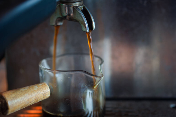 Großaufnahme von Espresso, der aus der Kaffeemaschine ausgeschenkt wird. Professionelle Kaffeezubereitung. - Foto, Bild