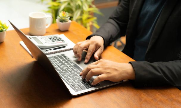 Businessman sitting at table with laptop calculator The notebook lay on his desk. Ready to move forward with business and communicate online via his mobile phone and notebook.close up.calculator. - Φωτογραφία, εικόνα