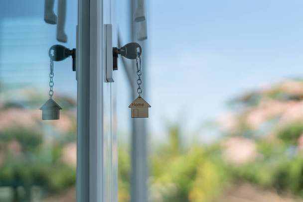 Landlord key for unlocking house is plugged into the door. Second hand house for rent and sale. keychain is blowing in the wind. mortgage for new home, buy, sell, renovate, investment, owner, estat - Foto, Imagen