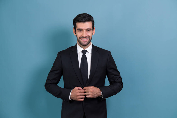 Stylish businessman in black suit posing confidently on isolated background, with a happy and optimistic smile as success and professionalism for businessman. Fervent - Foto, Bild