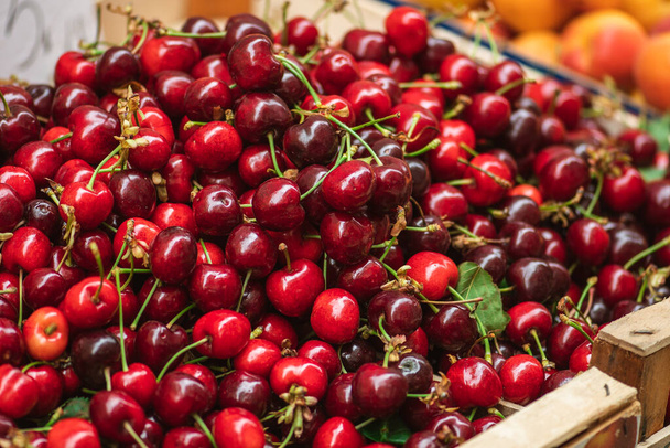 Fresh ripe red cherry or cherries fruit in a wooden box in a farmer agricultural open air market, seasonal healthy food. Concept of biological, bio products, bio ecology - Фото, зображення
