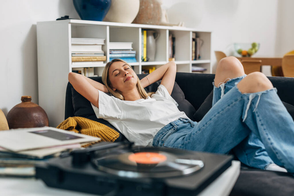 Caucasian woman relaxing with music from gramophone at home - Foto, Bild