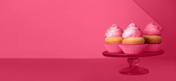 Stand avec de délicieux cupcakes sur fond magenta avec espace pour le texte - Photo, image