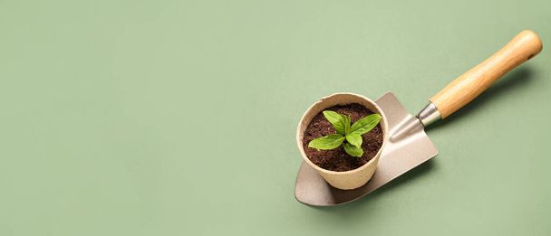 Maceta de turba con plántulas verdes y pala de jardinería sobre fondo verde con espacio para texto - Foto, Imagen