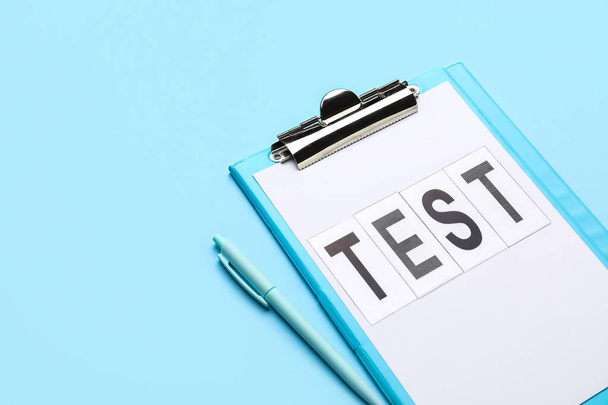 Буфер обмена со словом TEST и ручкой на синем фоне - Фото, изображение
