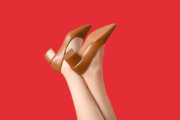 Женские ноги в стильной обуви на красном фоне, крупным планом - Фото, изображение