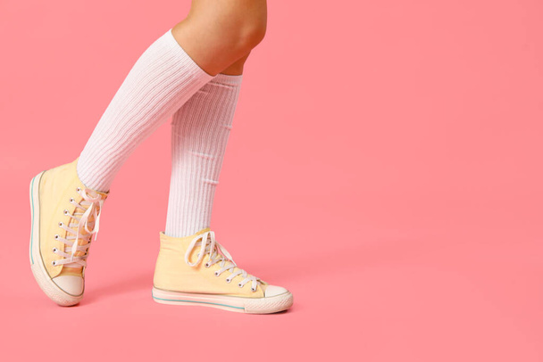 Kobiece nogi w stylowych gumowych butach na różowym tle, zbliżenie - Zdjęcie, obraz