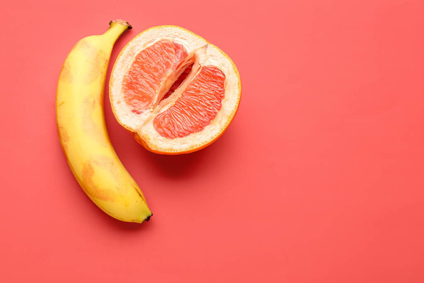 Banan z połową grejpfruta na czerwonym tle. Pojęcie płci - Zdjęcie, obraz