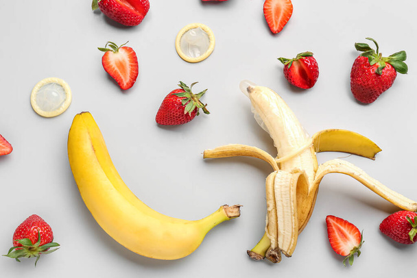 Erdbeeren mit Bananen und Kondomen auf hellem Hintergrund. Sexualkonzept - Foto, Bild