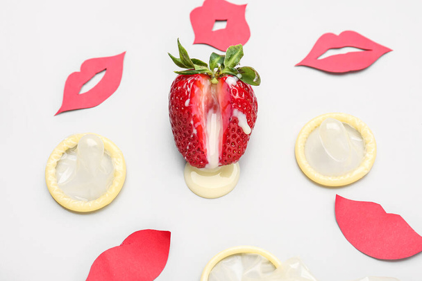 Strawberry with milk, condoms and paper lips on light background. Sex concept - Foto, afbeelding
