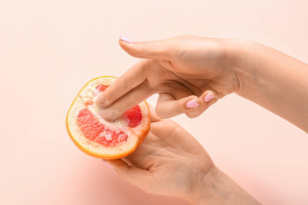 Woman with half of grapefruit on pink background, closeup. Sex concept - Φωτογραφία, εικόνα