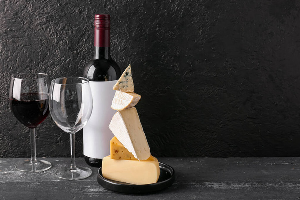 Διαφορετικό νόστιμο τυρί, ποτήρια και μπουκάλι με κρασί στο τραπέζι - Φωτογραφία, εικόνα