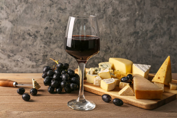 Glass with red wine and pieces of tasty cheese on table - Foto, Imagem