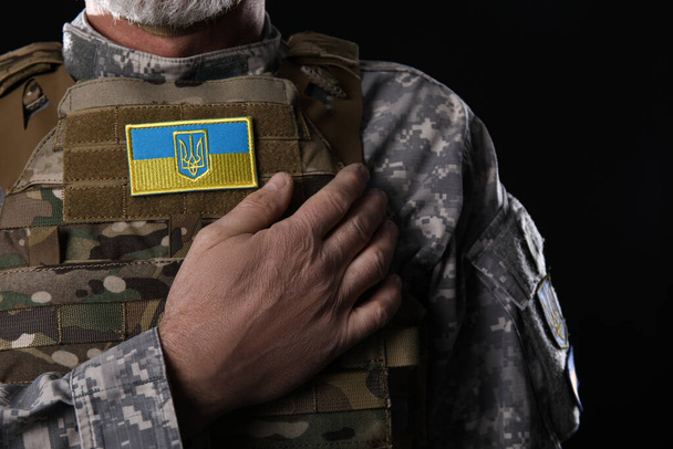 Зрелый солдат с украинской нашивкой на темном фоне, крупный план - Фото, изображение