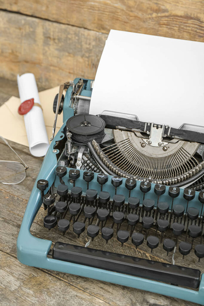 Vintage typewriter, eyeglasses and scroll with wax seal stamp on brown wooden background - Фото, зображення