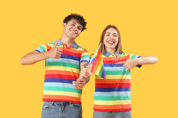 Junges Paar mit LGBT-Flagge auf gelbem Hintergrund - Foto, Bild