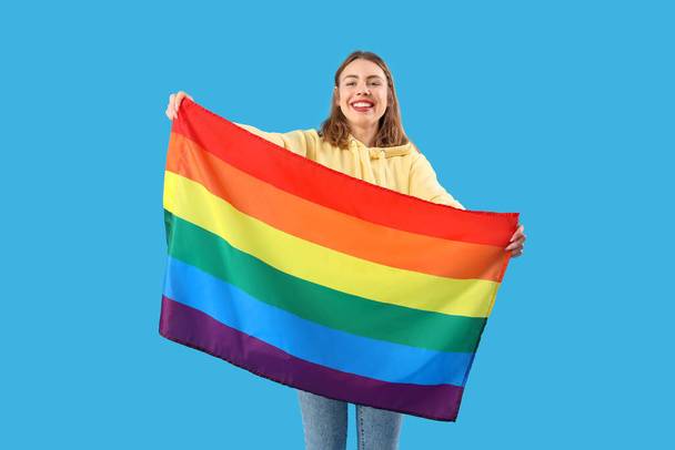 Jovem feliz com bandeira LGBT no fundo azul - Foto, Imagem
