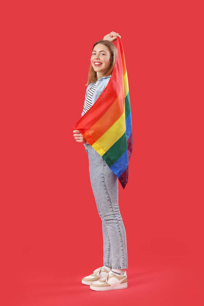 Jeune femme avec drapeau LGBT sur fond rouge - Photo, image