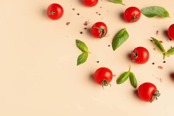 Tomates cereja maduros, folhas de manjericão, sal marinho e pimenta no fundo bege - Foto, Imagem