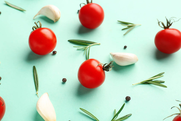 Ripe cherry tomatoes, rosemary, garlic and peppercorn on turquoise background, closeup - Photo, Image
