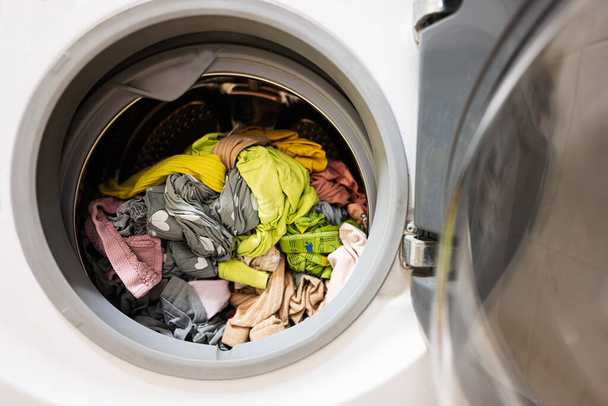 Washing machine with a lot of dirty clothes in the laundry room - Photo, image