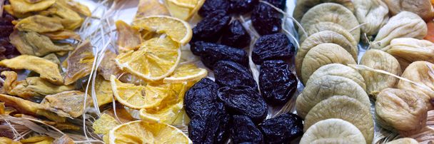 Fondo di frutta secca. Righe di datteri secchi, albicocche, limone, prugne secche e fichi. Foto di alta qualità - Foto, immagini