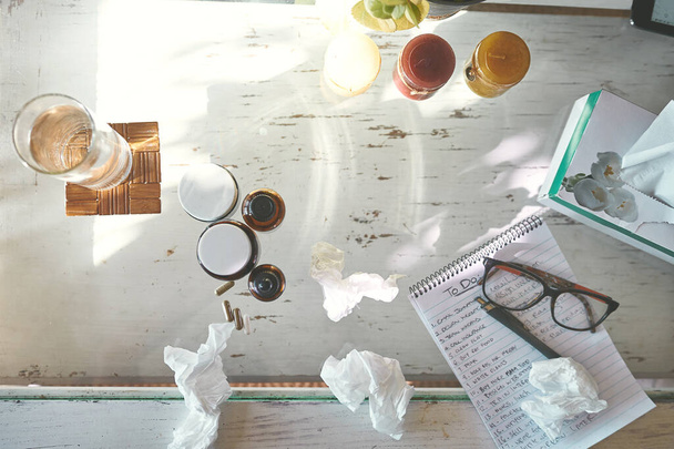 The get well soon starter pack. High angle shot of medication, tissues a notepad and glasses on a table at home - Foto, Imagen