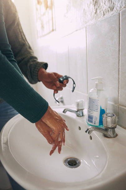 Las manos son las principales vías de transmisión de gérmenes. Primer plano de una mujer irreconocible lavándose las manos mientras se cronometraba con un reloj en un baño en casa - Foto, imagen