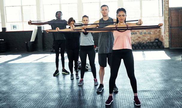 Spolu se potíme. fitness skupina cvičit s odporovými kapelami v jejich sezení v tělocvičně - Fotografie, Obrázek