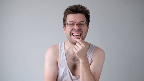 Um homem europeu sarcástico de óculos grandes ri e aponta o dedo para a câmera - Foto, Imagem