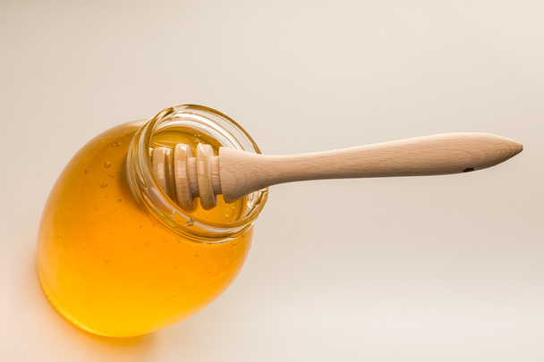Glass jar of honey with wooden drizzler  - Φωτογραφία, εικόνα
