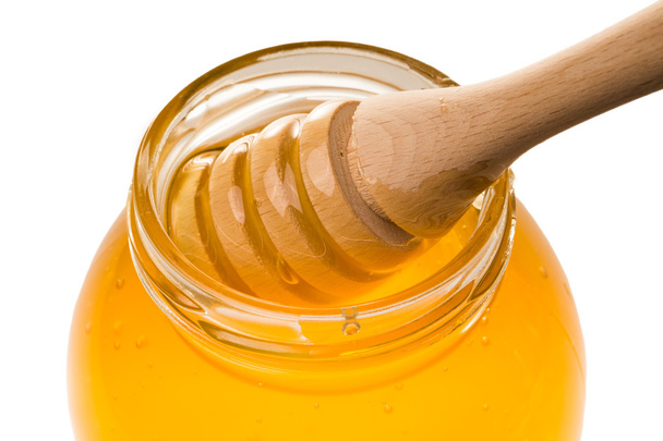 Glass jar of honey with wooden drizzler isolated on white backgr - Φωτογραφία, εικόνα