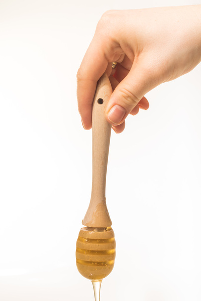 Honey dripping from a wooden honey dipper isolated on white back - Valokuva, kuva