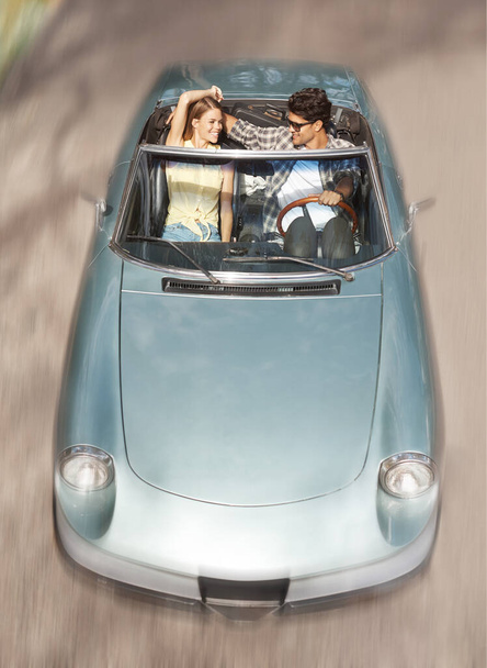 Чувствую ветер в волосах. Привлекательная молодая пара, едущая вместе на открытом спортивном автомобиле - Фото, изображение