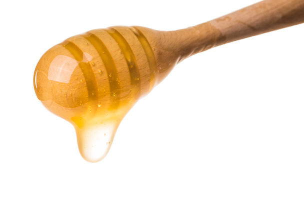 Honey dripping from a wooden honey dipper isolated on white back - Photo, Image