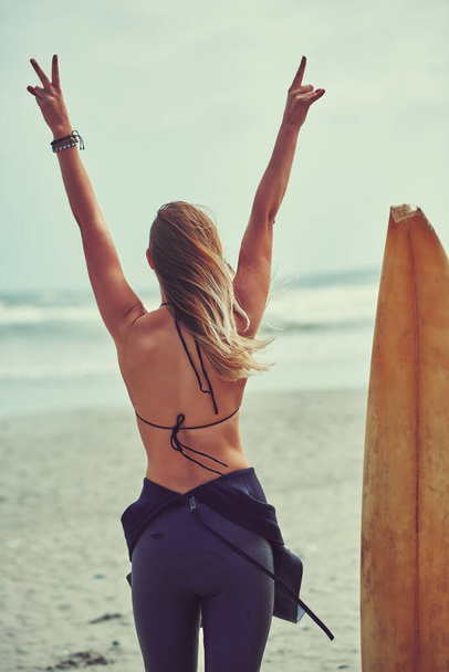 Surfs up. a beautiful young woman going for a surf at the beach - Foto, Bild