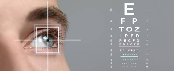 Vision test chart and laser reticle focused on man's eye against light grey background, closeup. Banner design - Fotoğraf, Görsel