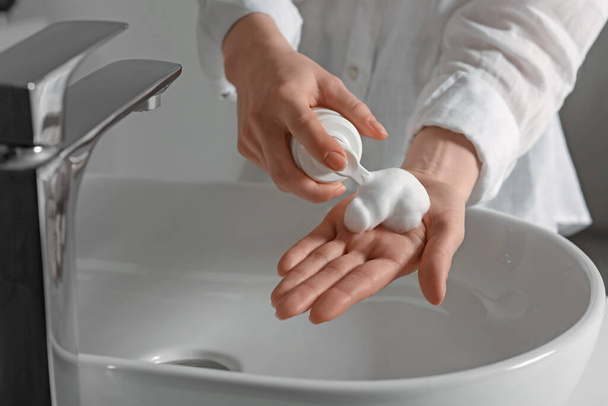 Woman washing hands with cleansing foam near sink in bathroom, closeup - Zdjęcie, obraz