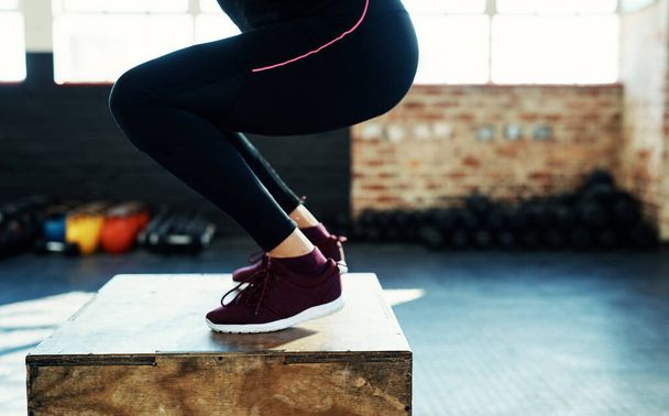 Не бійся невдач, бійся відсутності прогресу. невпізнавана жінка робить стрибок вправи на дерев'яному блоці в спортзалі
 - Фото, зображення
