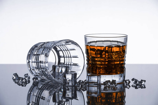 Kristály whiskey poharak egy tükröződő felületen. Elszigetelt tárgy. Drámai modern háttér. Kortárs design. - Fotó, kép