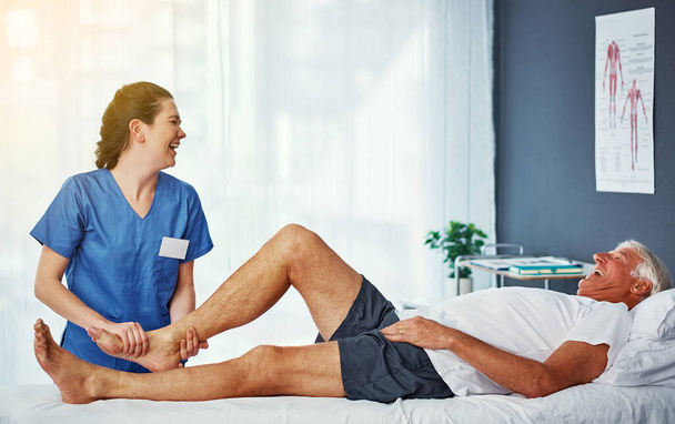 That tickles. a senior man working on his recovery with a female physiotherapist - Foto, Imagen