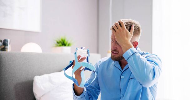 Shocked Young Man Holding CPAP Machine Mask - Фото, изображение