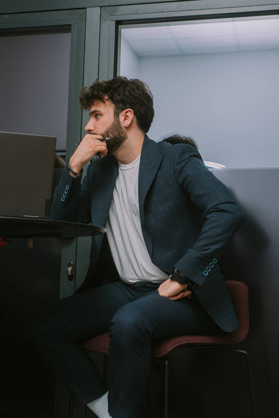 Стильний чоловічий бізнесмен, сидячи на стільці і нахиляючи голову на руку, слухаючи своїх колег
 - Фото, зображення