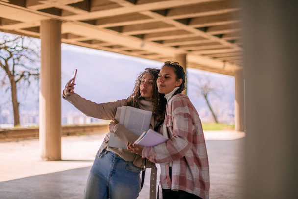 Una foto de dos chicas de la escuela tomando una selfie en el patio de la escuela - Foto, imagen