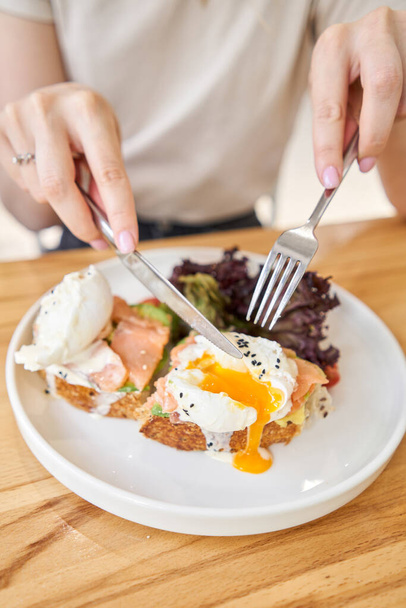 restaurant dish Brioche with poached egg with salmon and avocado. Delicious bread with greens. High quality photo - 写真・画像